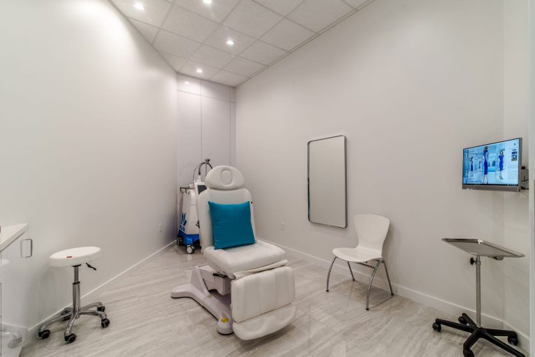 Modern medical spa treatment room with reclining patient chair, equipment, and wall-mounted monitor completed during a Houston medical build out.