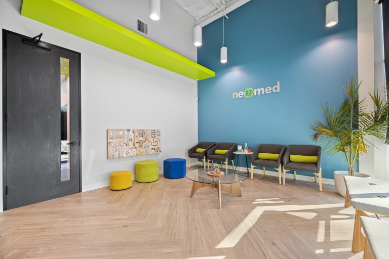 Modern NeoMed patient waiting room with bold branded accent wall, seating, and contemporary finishes completed during a Houston medical build out.