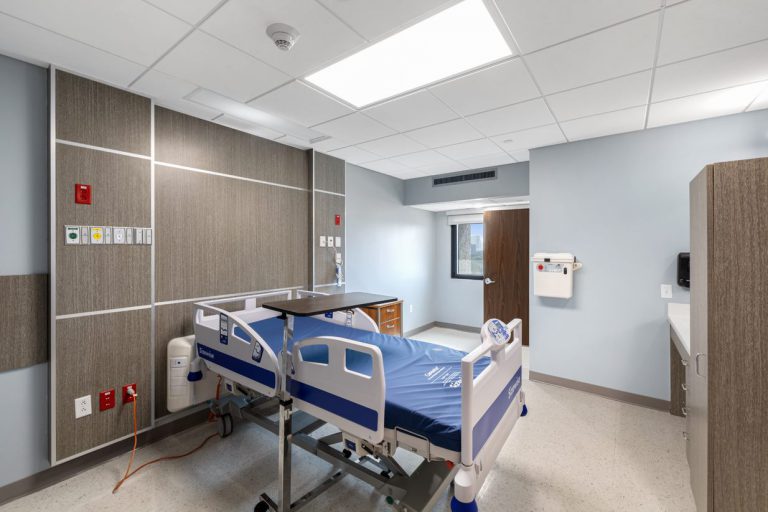 Newly renovated hospital patient room with wood-paneled headwall, medical bed, and modern finishes completed during a Houston medical build out.