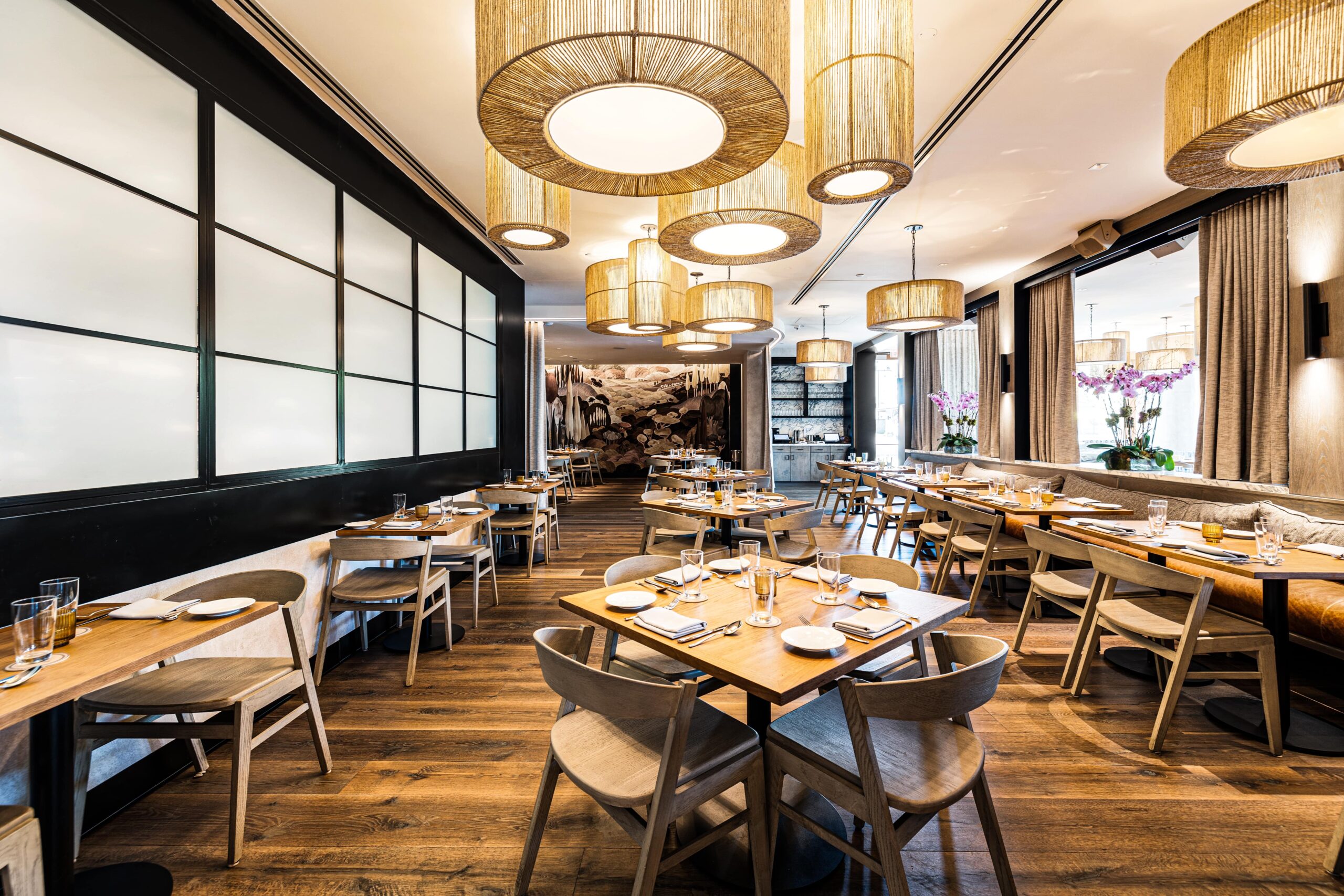 Luxury restaurant dining room featuring custom woven pendant lighting, hardwood floors, and modern table settings.