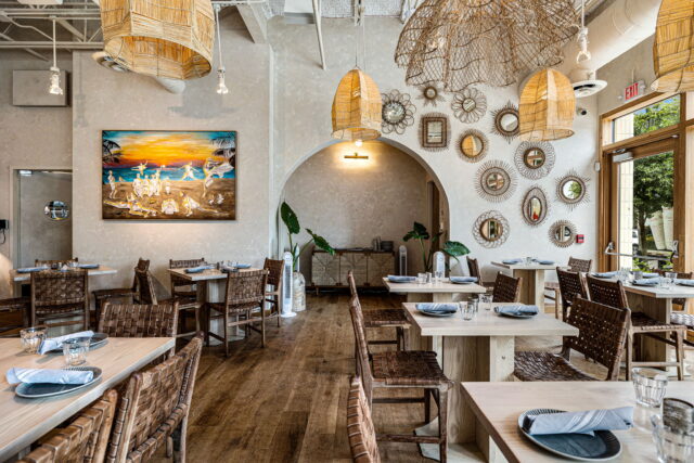 Commercial restaurant interior build-out with bohemian coastal design, rattan lighting, and natural wood finishes