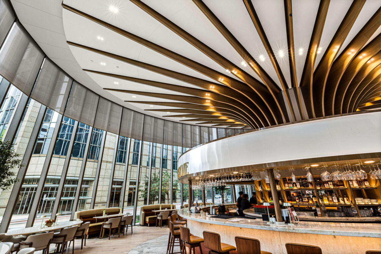 Elegant modern restaurant interior with a curved architectural ceiling, circular bar, and floor-to-ceiling windows